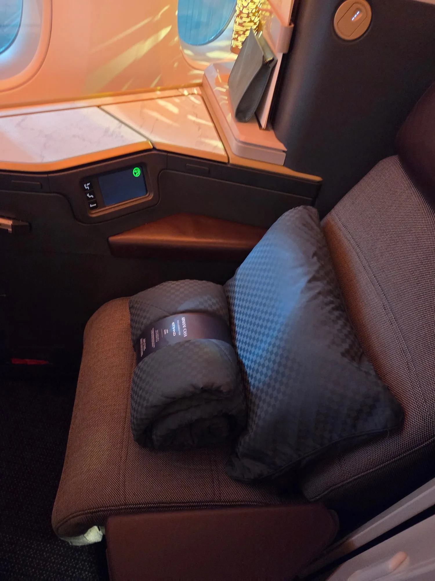 Business class seat with pillow and blanket under warm cabin lighting
