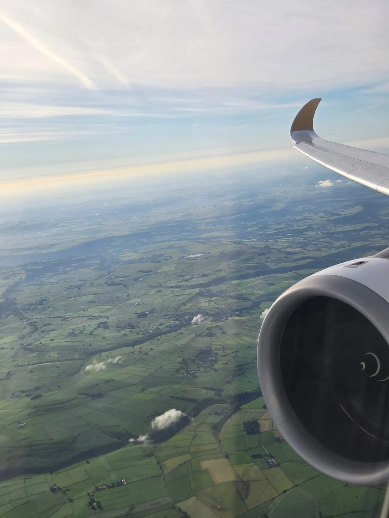 Wing and engine over green fields on the approach to Manchester