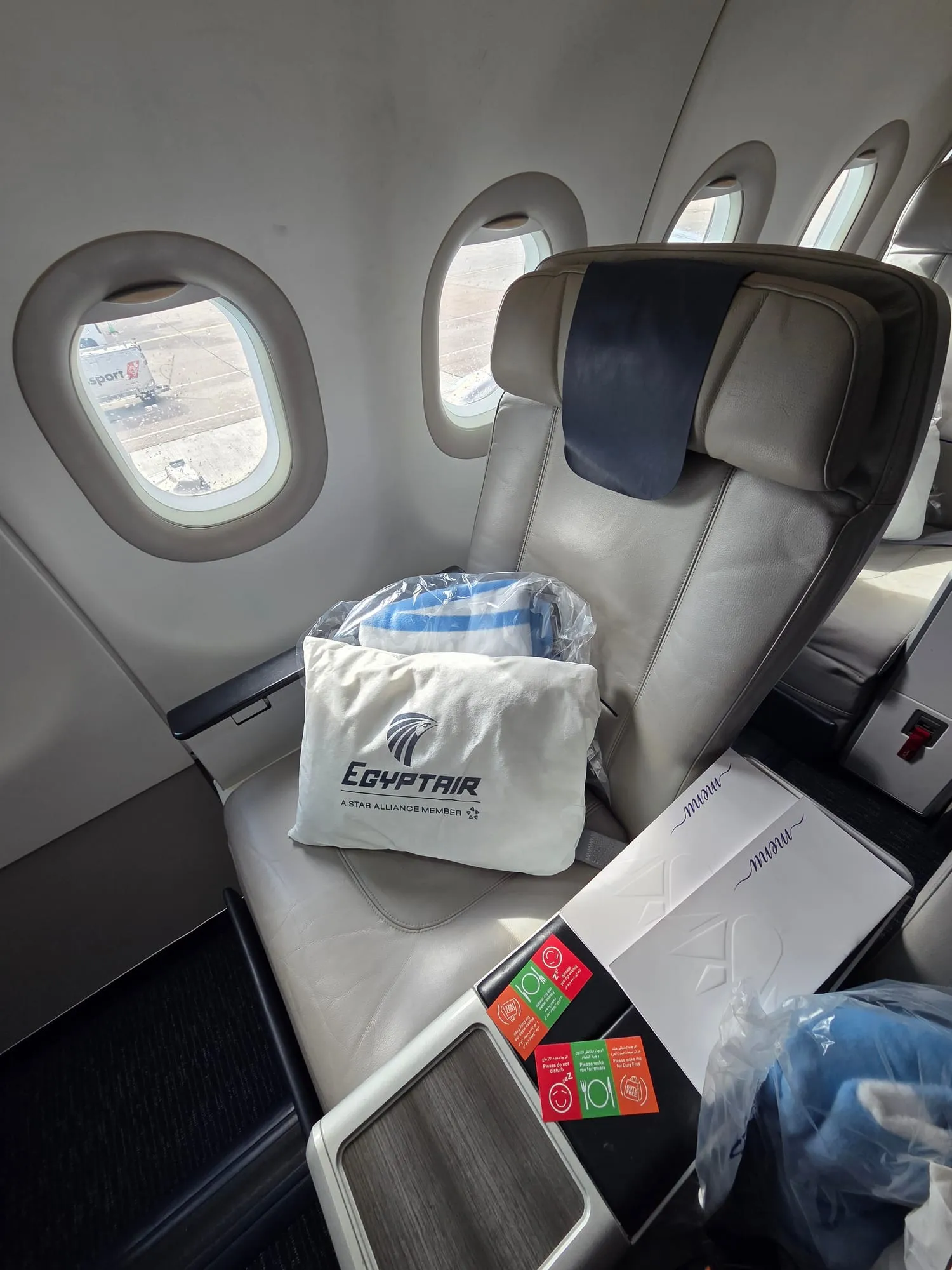 EgyptAir business class seat with pillow and amenity kit, by the window