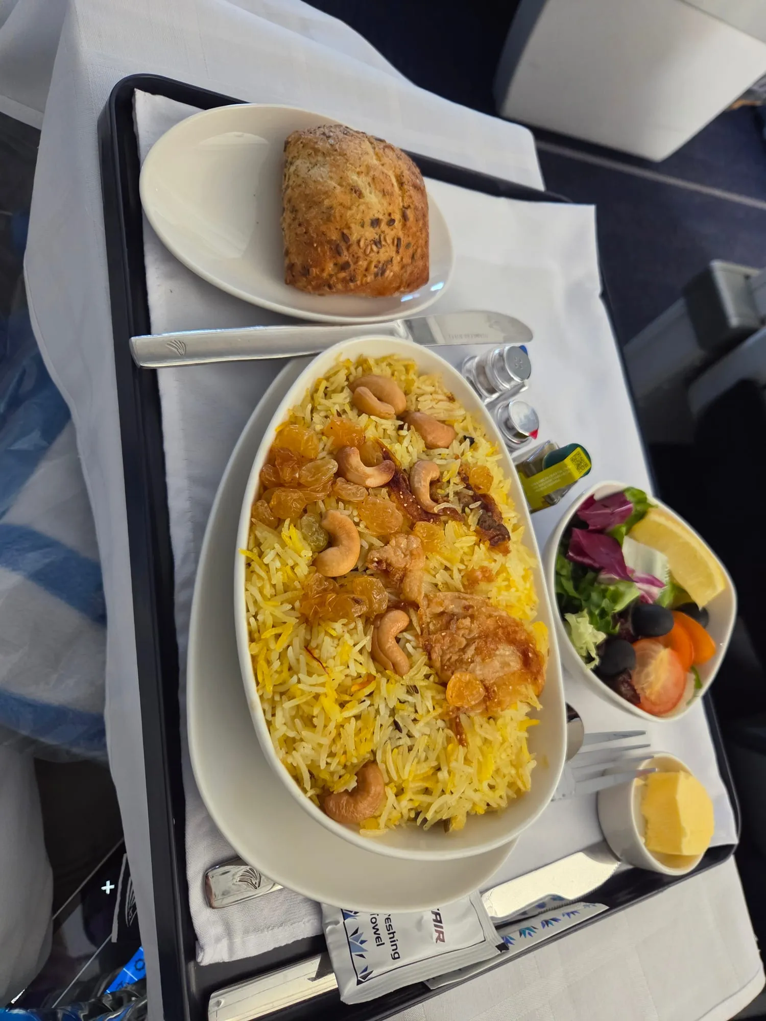 Main course on the tray table: rice with prawns, bread roll and salad